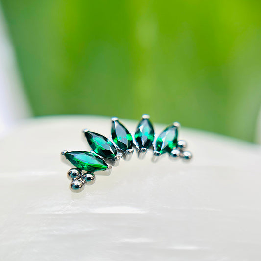 Piercing cluster con circones verdes y ornamentos.